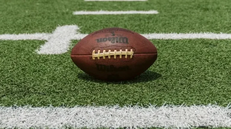 American football laying on green football field